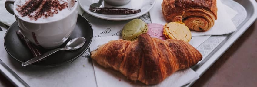 Some croissants and macaroons near the cups of coffee